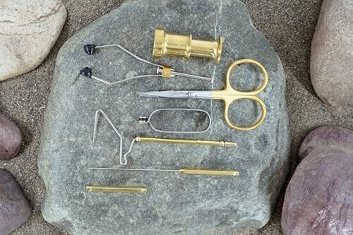 Fly tying tools arranged on a rock surface.