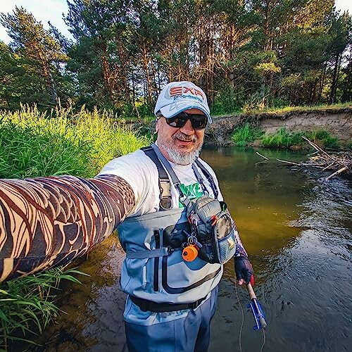 Man fishing in a river, wearing a hat and sunglasses.