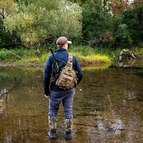 Man standing in river with fishing gear and backpack